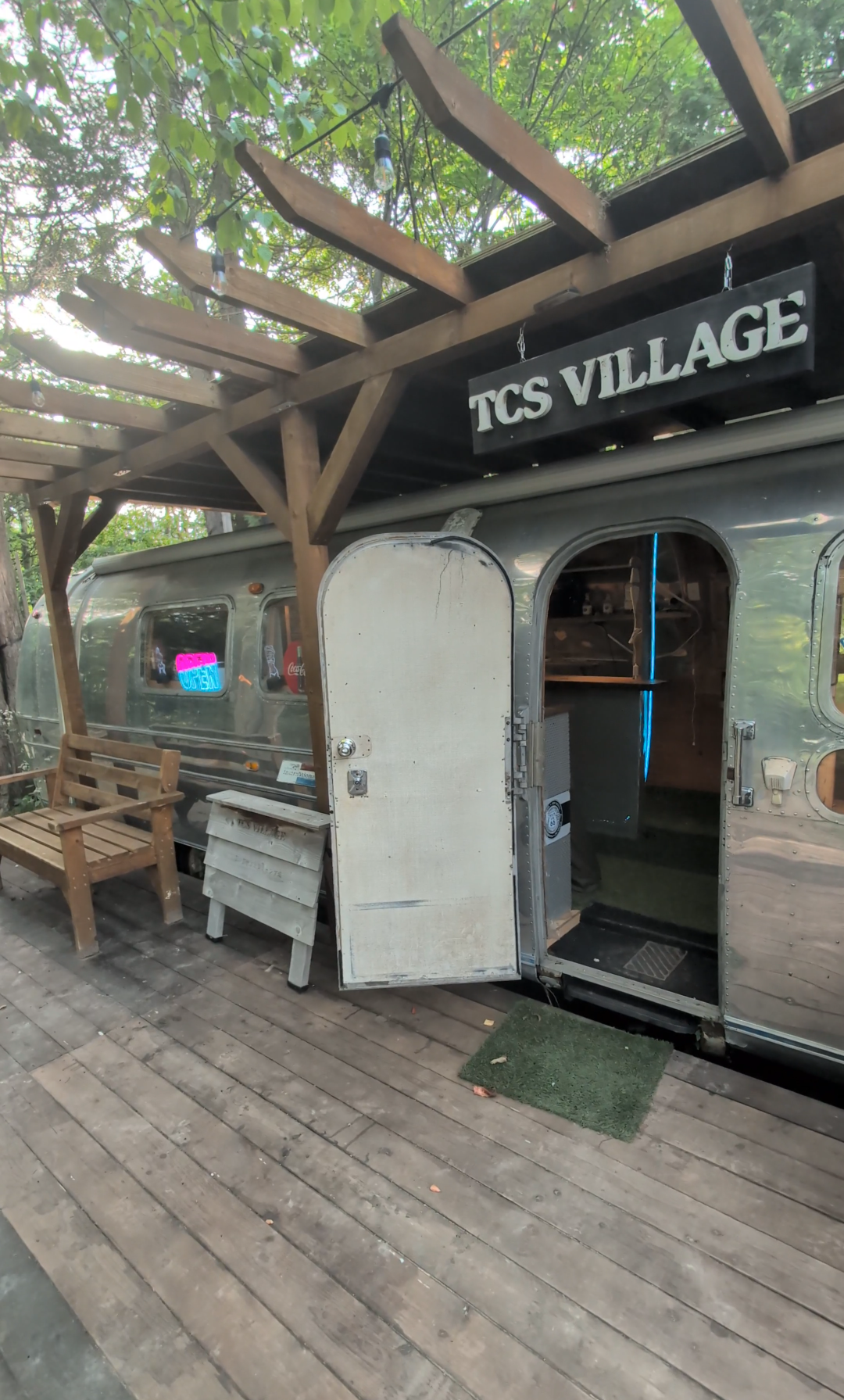 TCS VILLAGEの看板が掲げられたエアストリームBARの入口。ネオンサインが灯る